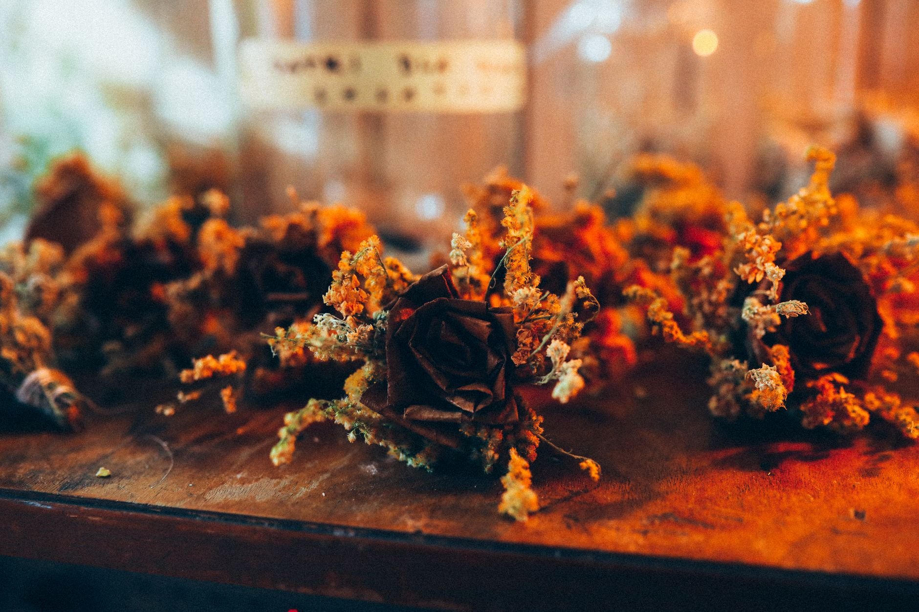 Warm-toned close-up of delicate dried flowers on a wooden surface.